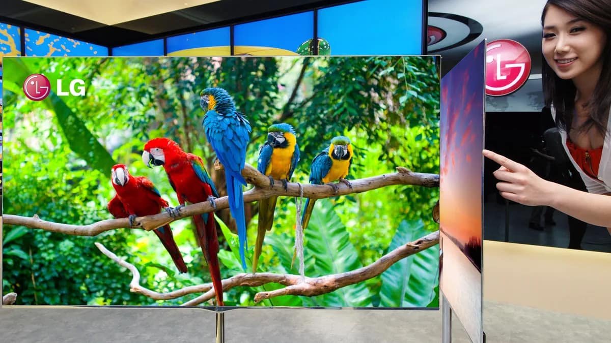 Large wall-mounted OLED TV in a living room with a soundbar below and a game controller on the table