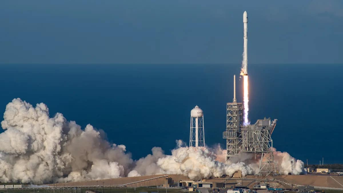 Illustration of a rocket on a damaged launch pad with construction cranes behind it at dusk