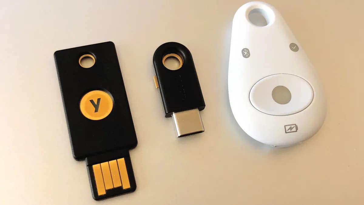 A USB hardware security key resting on a keyboard next to a laptop