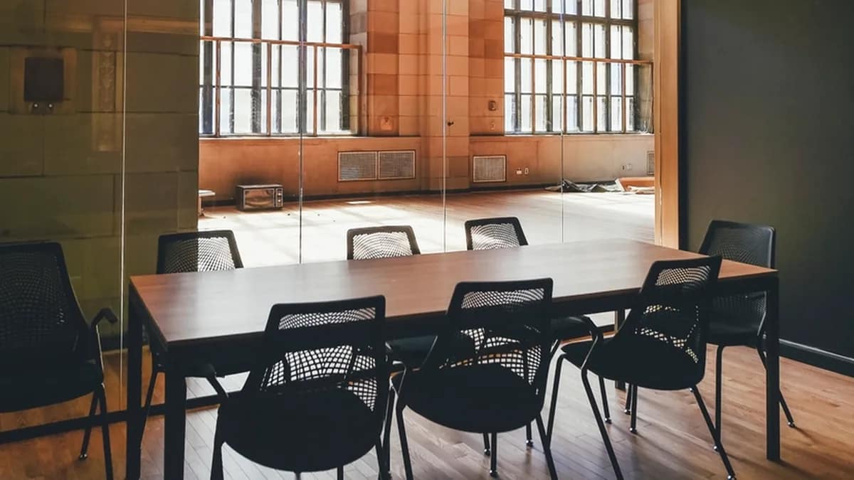 Illustration of an empty chair at the head of a boardroom table with a world map behind it