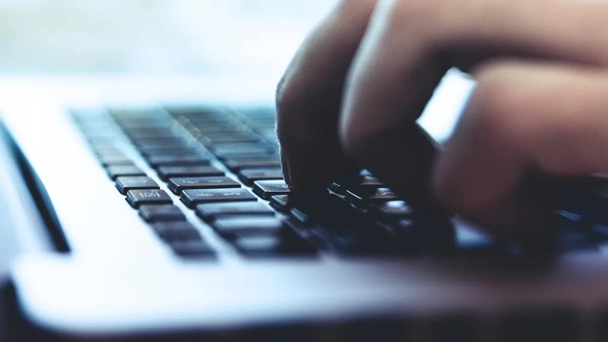 Administrator reviewing server logs on a laptop at a desk